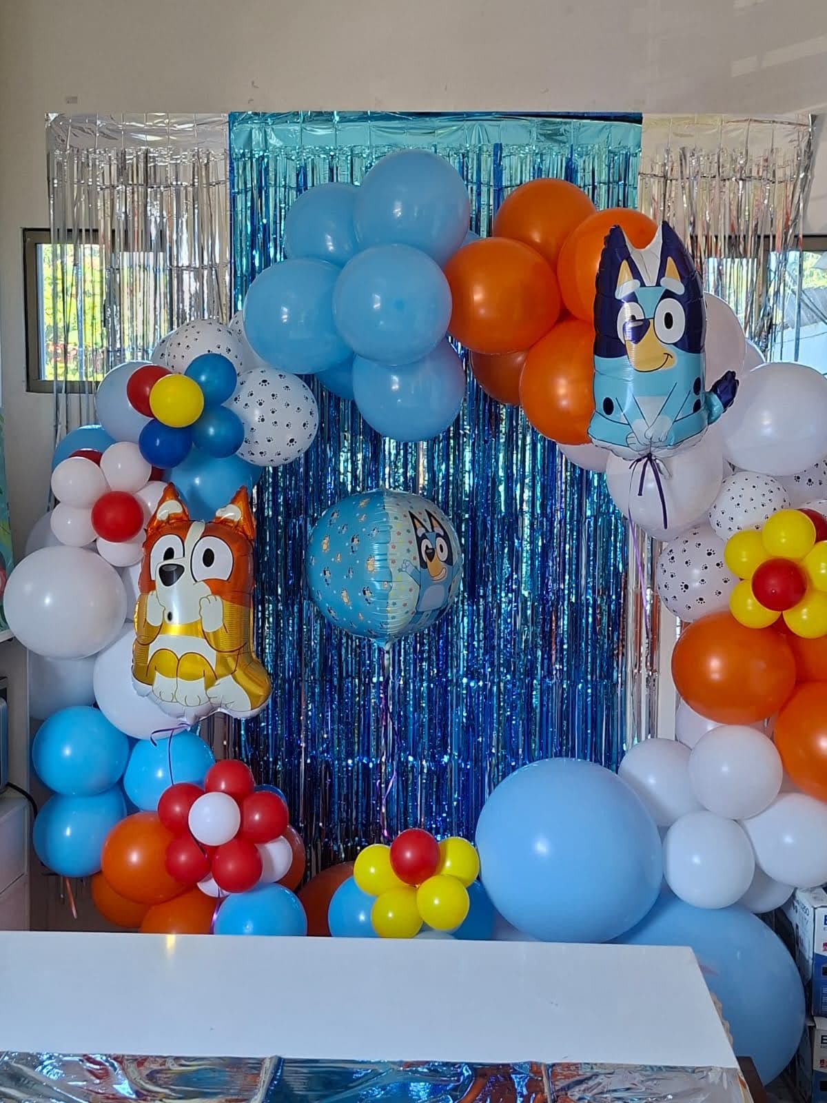 Decoración colorida con globos azules y naranjas con personajes de Bluey para fiesta infantil