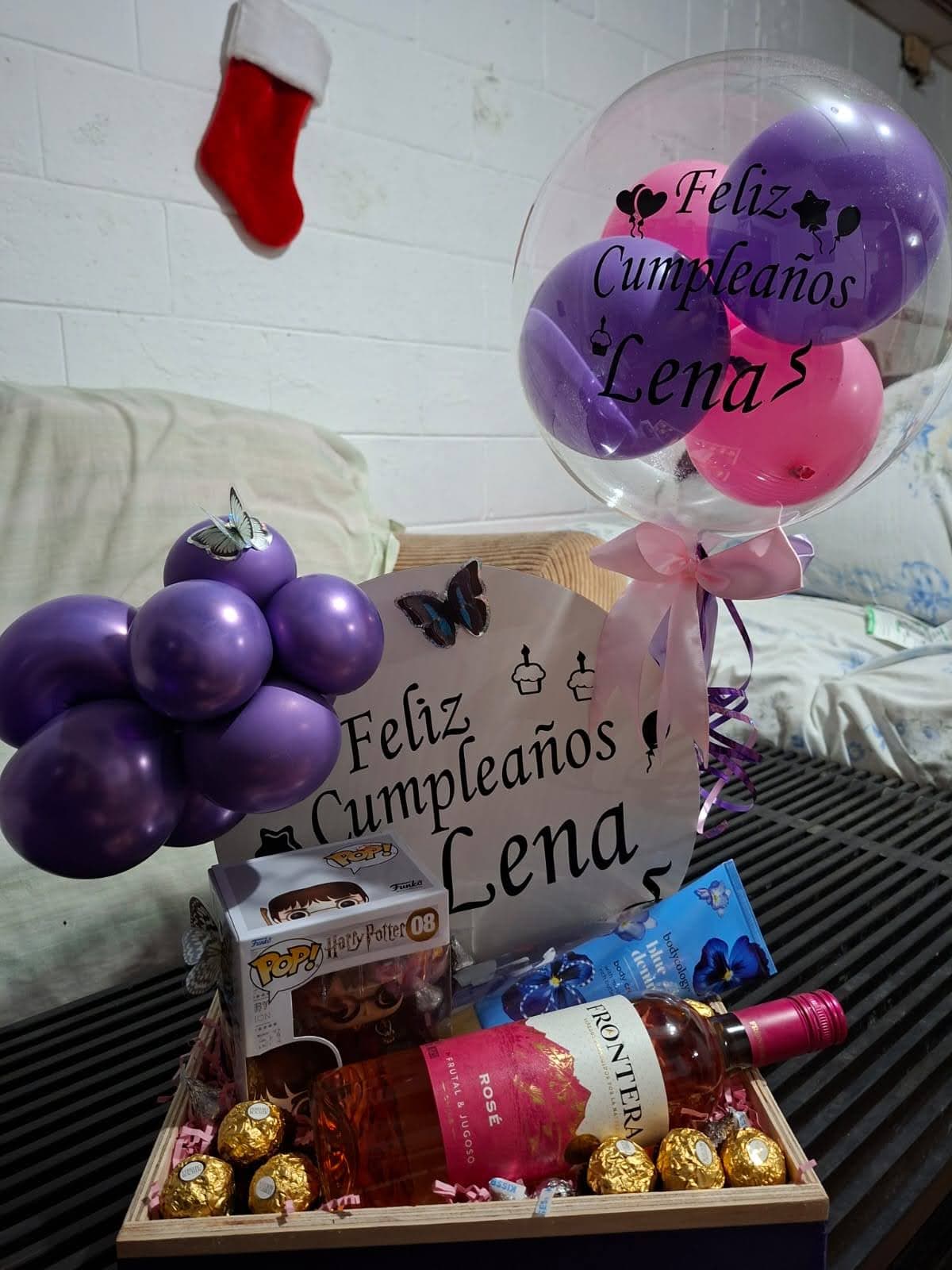 Caja regalo con cupcake, globo burbuja transparente y globos morados con el nombre de la festejada
