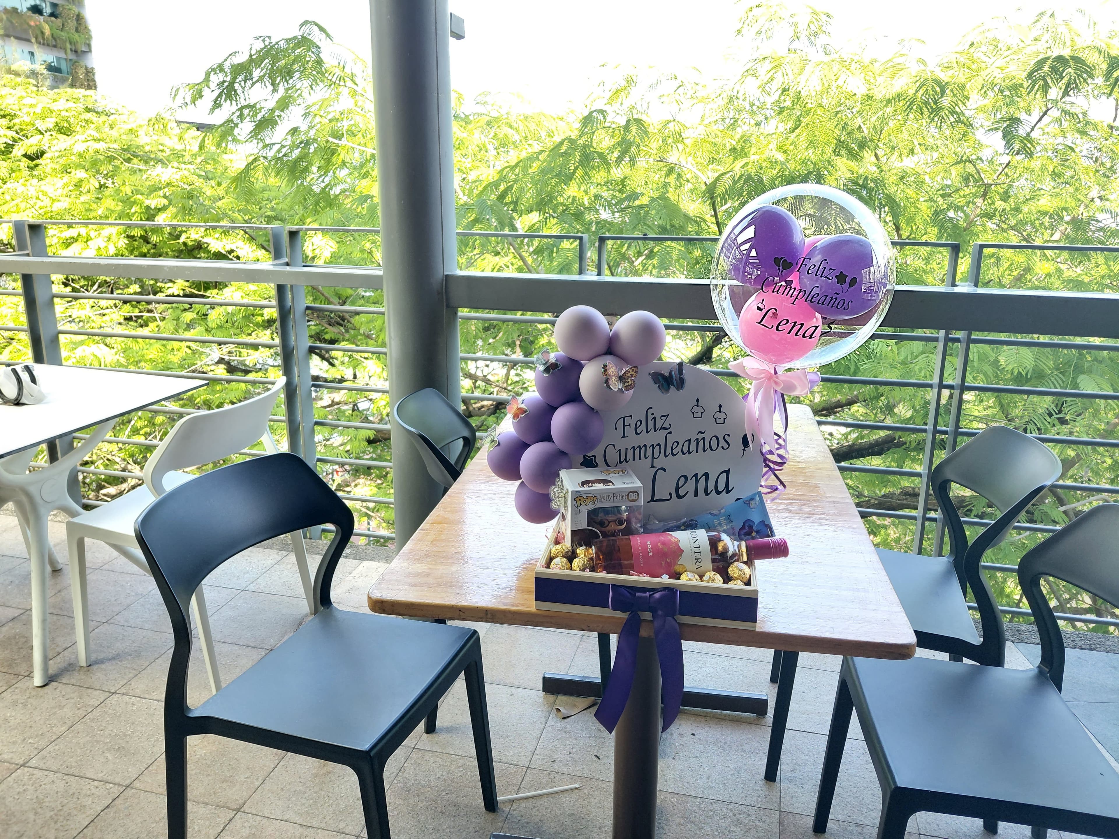 Caja de regalo con arreglo de cupcakes, globo burbuja y globos morados para festejar un cumpleaños